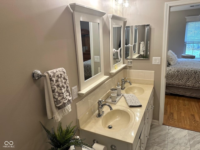 ensuite bathroom with double vanity, marble finish floor, ensuite bath, and a sink