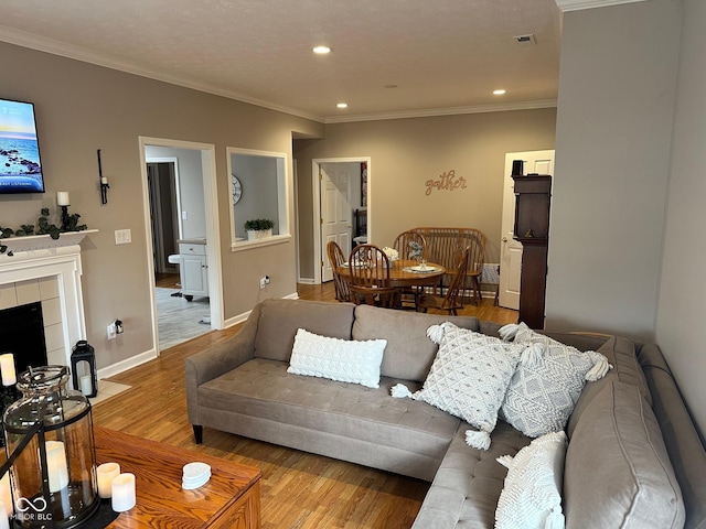 living area with crown molding, baseboards, recessed lighting, a tile fireplace, and wood finished floors