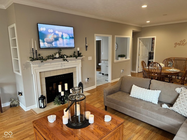 living room with baseboards, ornamental molding, recessed lighting, light wood-style flooring, and a tile fireplace