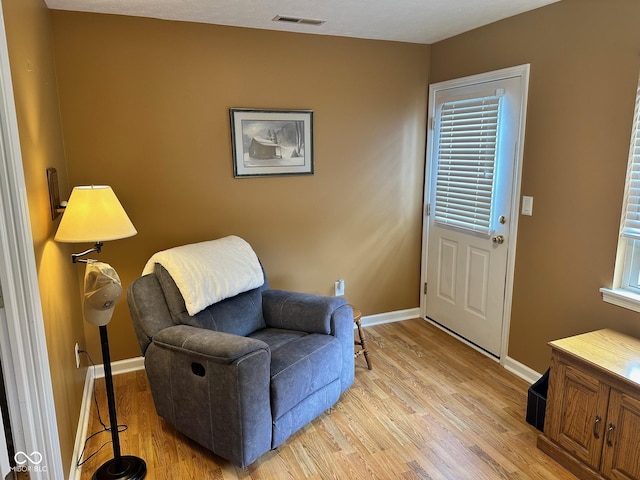 sitting room with light wood-style floors, visible vents, and baseboards