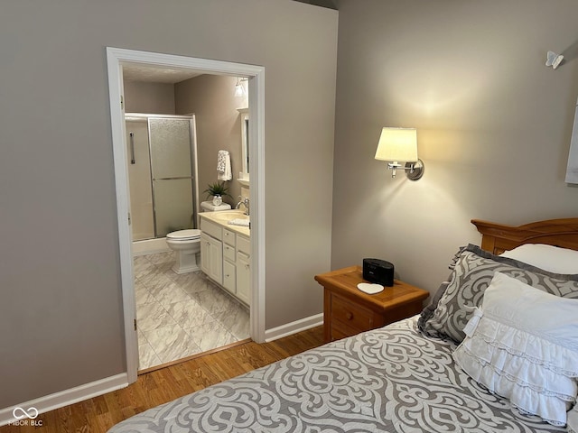 bedroom featuring a sink, connected bathroom, baseboards, and light wood-style floors