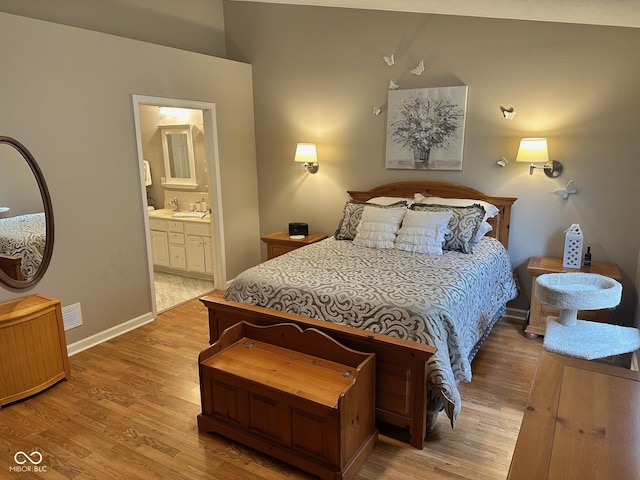 bedroom with a sink, visible vents, connected bathroom, and light wood-style flooring