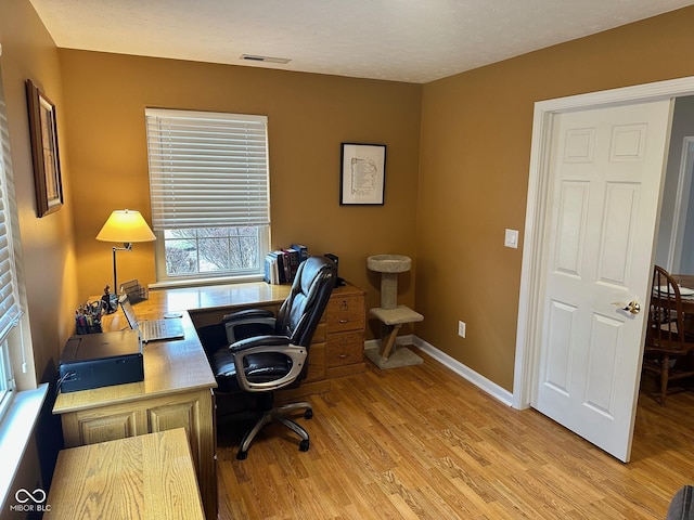 office space with light wood-style flooring, baseboards, and visible vents