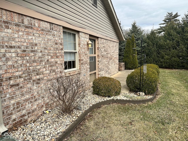 view of side of home with a yard and brick siding