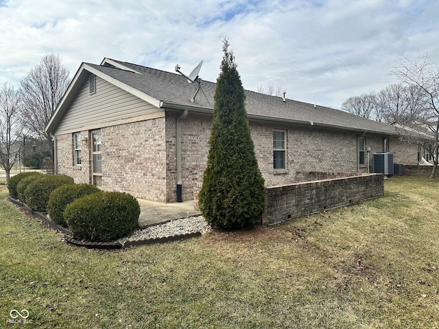 view of home's exterior with a patio, a shingled roof, central air condition unit, a lawn, and brick siding