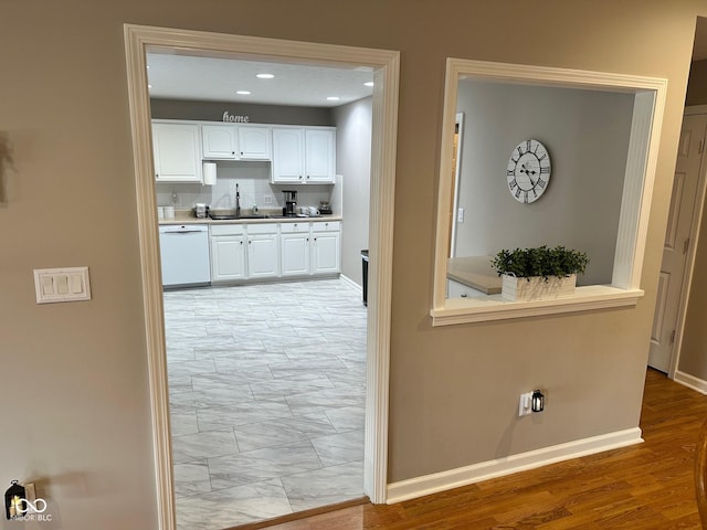 hallway with recessed lighting, baseboards, light wood finished floors, and a sink