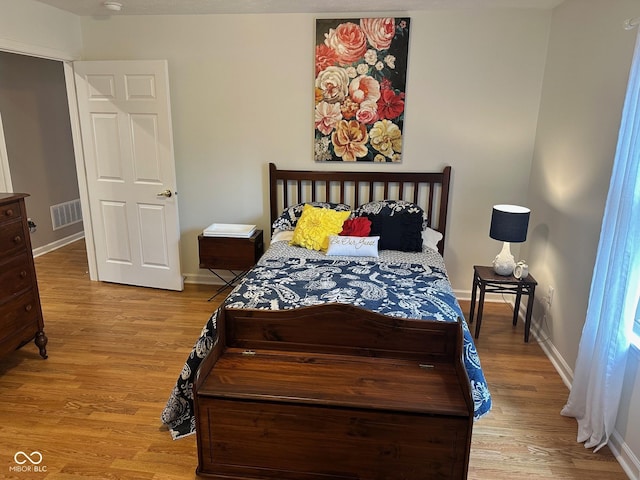 bedroom with visible vents, light wood-style flooring, and baseboards