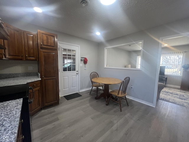 dining room with baseboards, light wood-style floors, and a textured ceiling