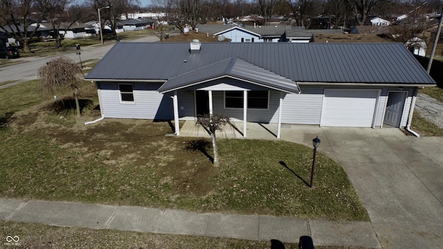 view of front of home with a front lawn, an attached garage, driveway, and metal roof