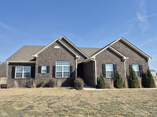 single story home featuring a front lawn, brick siding, and a shingled roof