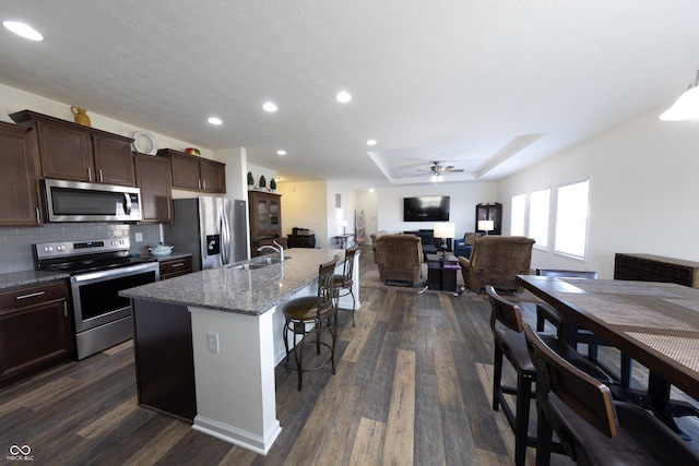 kitchen featuring a breakfast bar, dark wood-style flooring, stainless steel appliances, and a sink