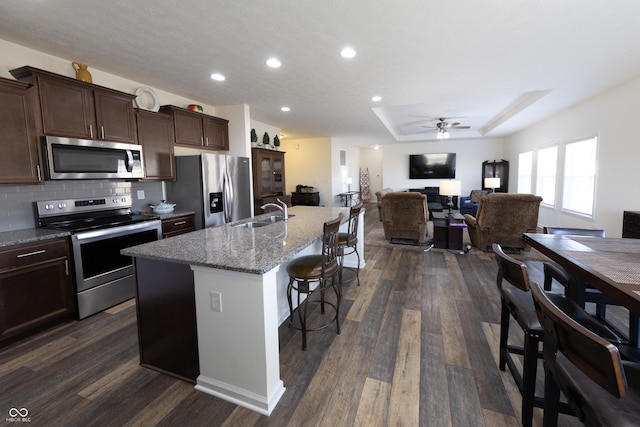 kitchen featuring dark wood-style floors, a kitchen breakfast bar, stainless steel appliances, and a sink