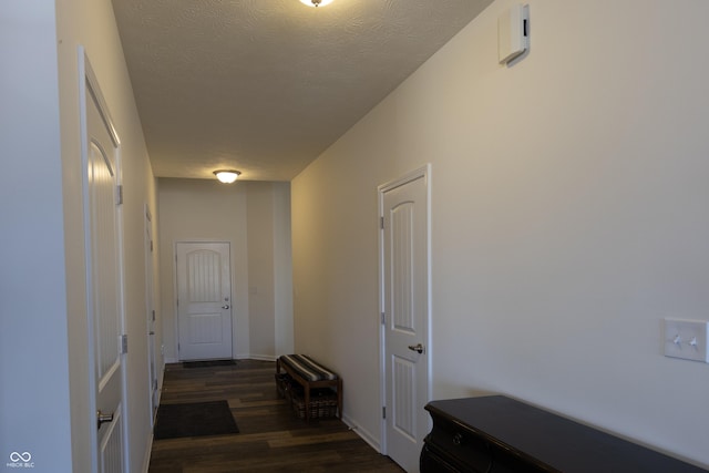 corridor with a textured ceiling and dark wood-type flooring