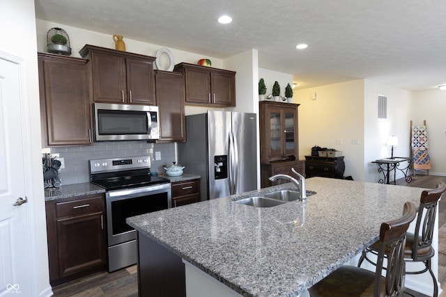 kitchen with visible vents, a sink, stainless steel appliances, decorative backsplash, and dark wood-style flooring