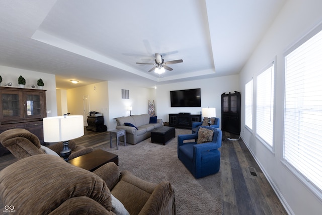 living area with visible vents, a raised ceiling, baseboards, and dark wood-style flooring