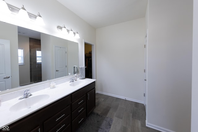 full bathroom featuring double vanity, wood finished floors, baseboards, and a sink