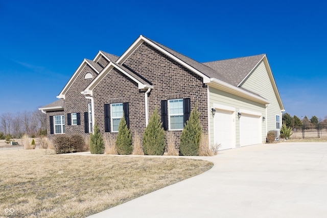 view of front of property featuring brick siding, fence, a front yard, a garage, and driveway