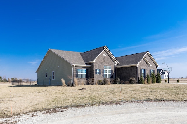 view of front of property with brick siding, roof with shingles, and fence