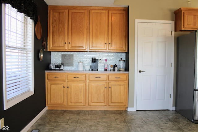 kitchen with freestanding refrigerator, light countertops, plenty of natural light, and backsplash