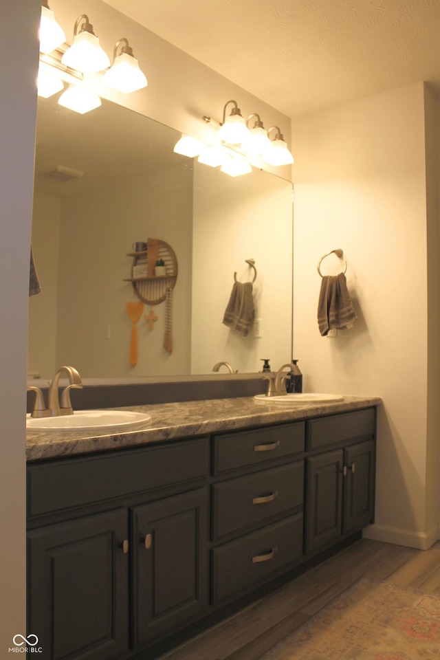 full bathroom with double vanity, a sink, and wood finished floors