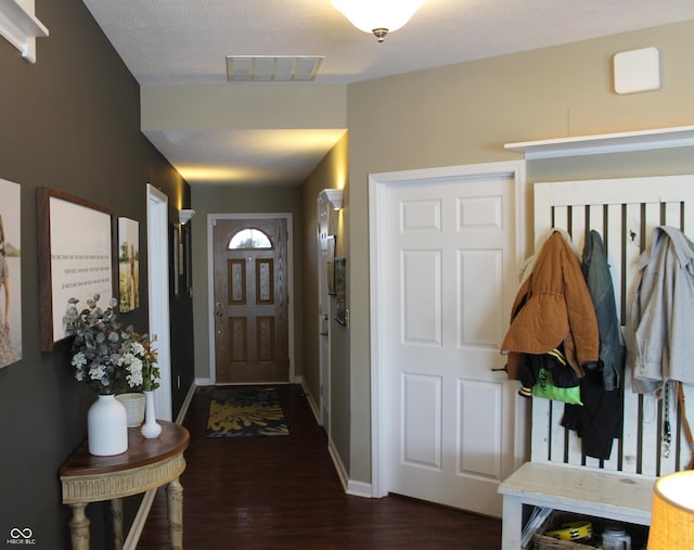 entryway with dark wood-style floors, visible vents, and baseboards