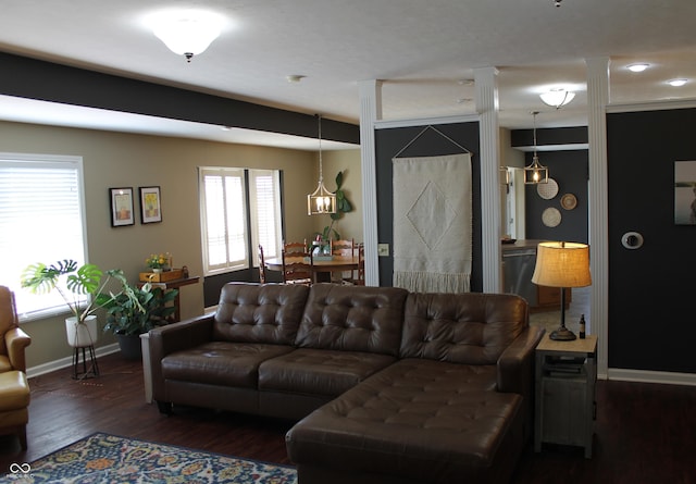 living area with decorative columns, baseboards, and wood finished floors