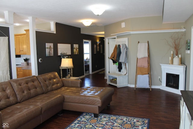 living area with a glass covered fireplace, dark wood finished floors, and baseboards