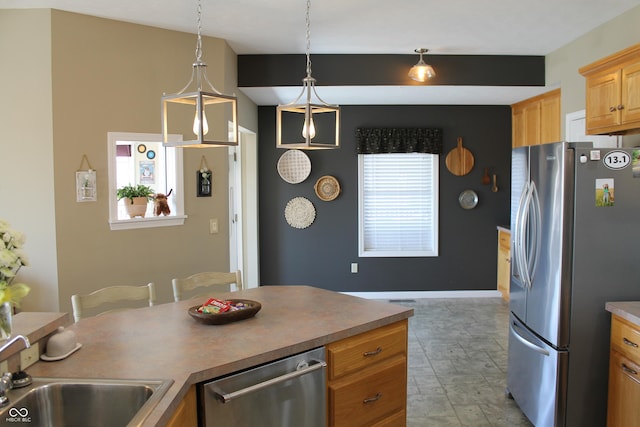 kitchen with appliances with stainless steel finishes, plenty of natural light, a sink, and decorative light fixtures