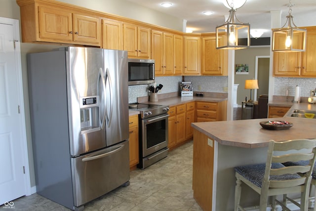 kitchen with stainless steel appliances, a breakfast bar, a sink, tasteful backsplash, and pendant lighting