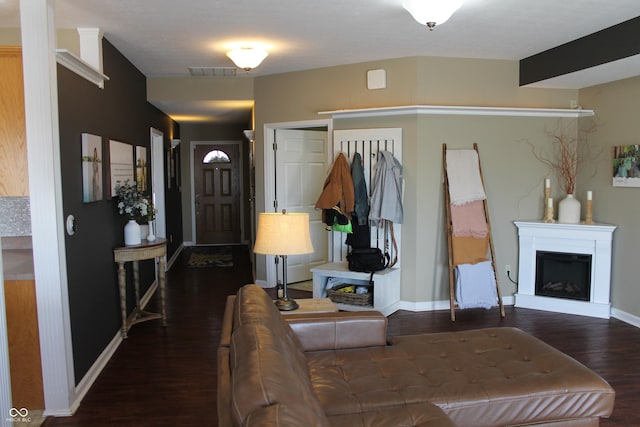 entrance foyer with a fireplace with raised hearth, wood finished floors, visible vents, and baseboards