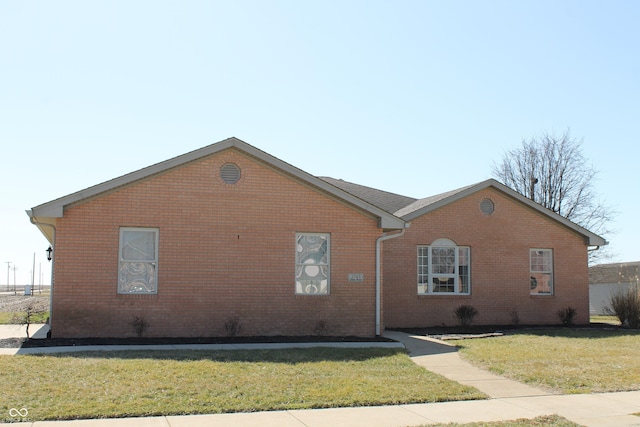 view of side of home featuring brick siding and a lawn