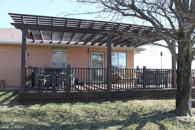 rear view of house featuring brick siding, a wooden deck, and a pergola