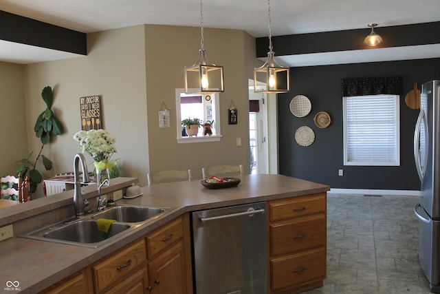 kitchen with stainless steel appliances, a sink, baseboards, hanging light fixtures, and brown cabinets