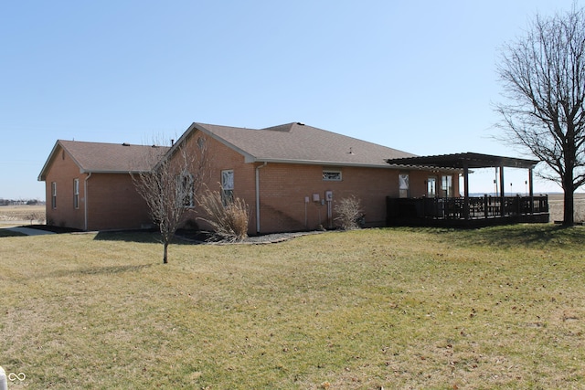 view of side of property with a lawn, a pergola, and brick siding