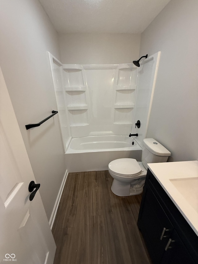 bathroom with toilet, wood finished floors, vanity, baseboards, and shower / bathing tub combination