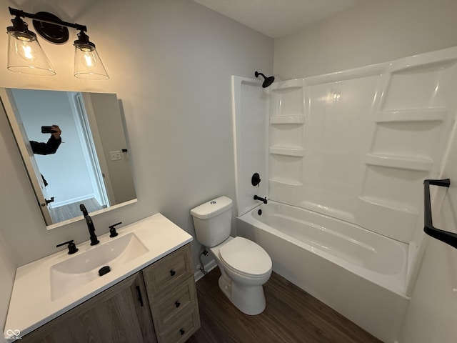 full bathroom with washtub / shower combination, vanity, toilet, and wood finished floors