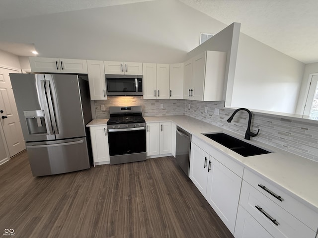 kitchen with lofted ceiling, appliances with stainless steel finishes, dark wood-style flooring, light countertops, and a sink