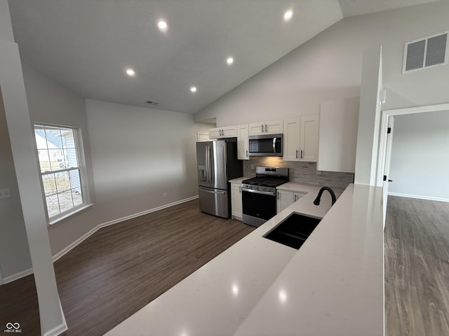 kitchen with stainless steel appliances, visible vents, dark wood-type flooring, white cabinets, and a sink