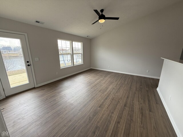 unfurnished living room with baseboards, visible vents, a ceiling fan, dark wood-style flooring, and a textured ceiling