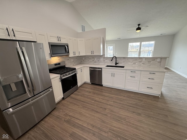 kitchen featuring white cabinets, a peninsula, stainless steel appliances, light countertops, and a sink