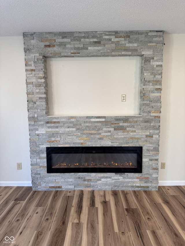 details featuring a textured ceiling, a fireplace, and wood finished floors