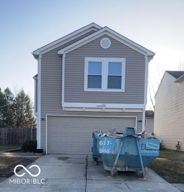 view of front of home with driveway, an attached garage, and fence