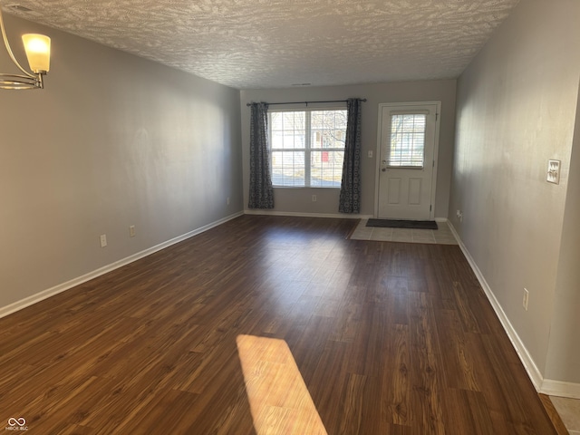 interior space featuring dark wood-style floors, a textured ceiling, and baseboards