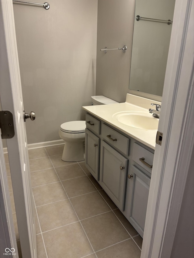 half bath featuring tile patterned floors, baseboards, toilet, and vanity