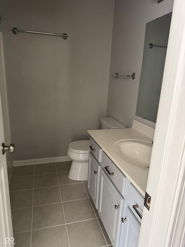 bathroom with baseboards, toilet, vanity, and tile patterned flooring