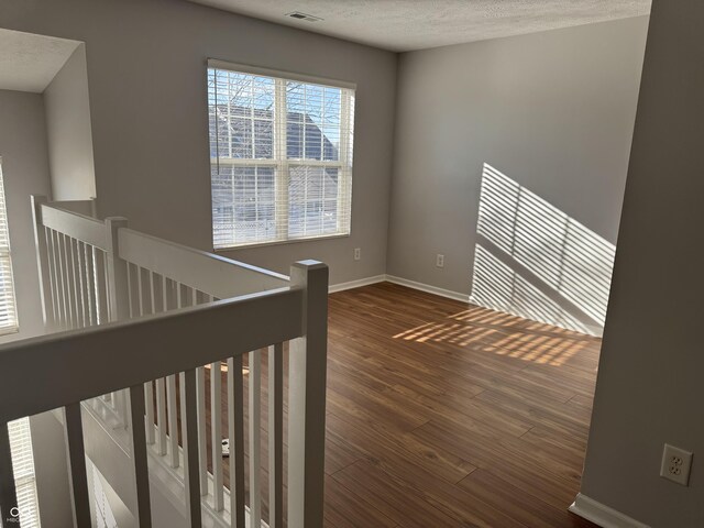 interior space featuring a textured ceiling, wood finished floors, visible vents, and baseboards