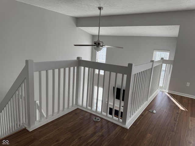 hallway featuring an upstairs landing, a textured ceiling, lofted ceiling, and wood finished floors