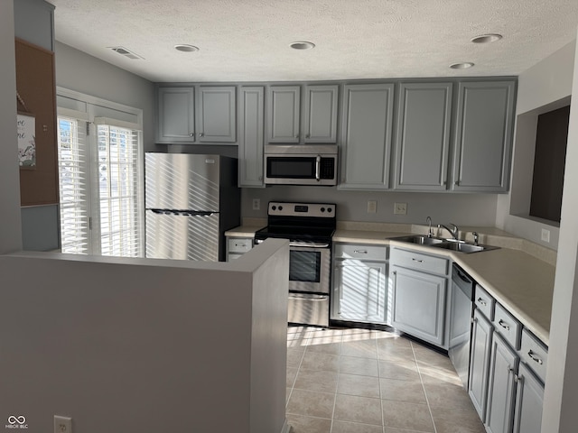 kitchen featuring a sink, stainless steel appliances, visible vents, and gray cabinets