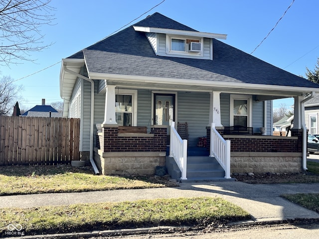 bungalow featuring a porch, fence, and roof with shingles