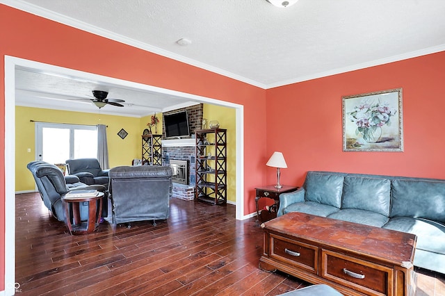 living room featuring a brick fireplace, baseboards, ornamental molding, dark wood-style floors, and a ceiling fan